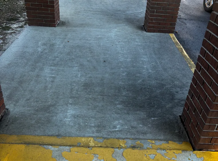 Covered commercial entrance with darkened, stained concrete