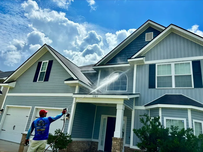 Two story house being soft washed from ground level