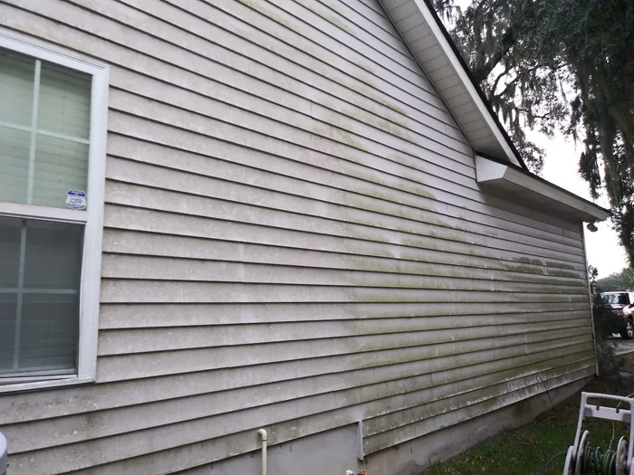 House siding part way through a soft wash, clean and dirty side by side