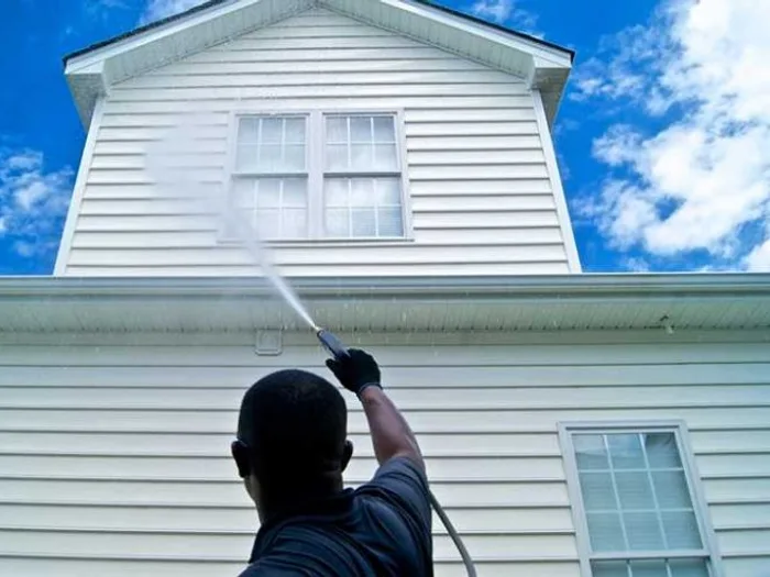 Soft washing the upper siding of a two story home from the ground